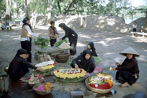 Hà Nội giữa thập niên 1960, những bà cụ bán vòng hoa tang và rau bên bờ Hồ Gươm.