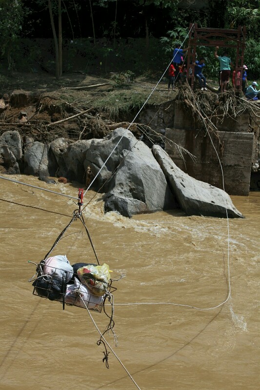 
Đồ cứu trợ được kéo ròng rọc qua nơi cây cầu treo đã bị cuốn trôi.
