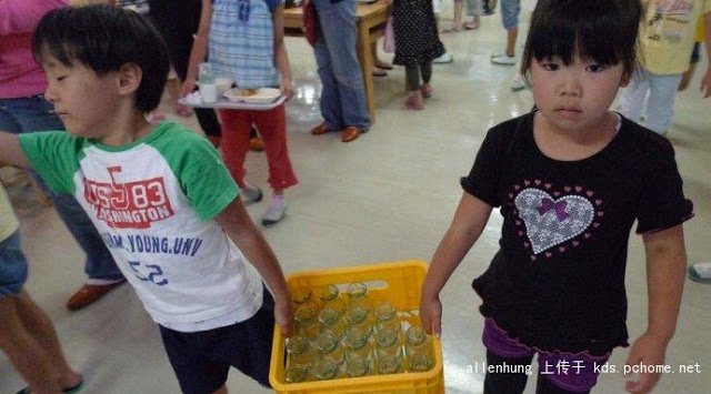 
Hai em học sinh Nhật Bản đang khiêng khay vỏ chai sữa.

