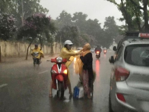 
Hành động mặc áo mưa cho bà cụ không quen biết của cô gái trẻ gây nhiều tranh cãi (Ảnh:Facebook)

