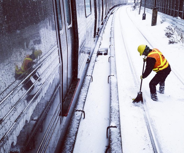 
Công nhân dọn tuyết phủ trắng các đường ray ở đường West End, Brooklyn.
