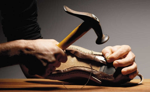 Nghệ nhân đóng đinh vào đế giày để cố định phần da vào khuôn gỗ