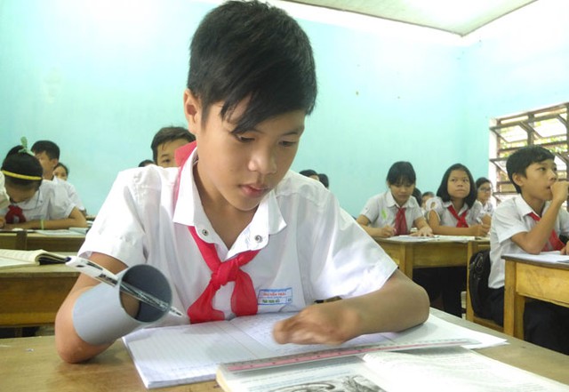 
Em Phan Trọng Hiếu dùng ống nhựa thay bàn tay để viết tiếp ước mơ con chữ của mình.
