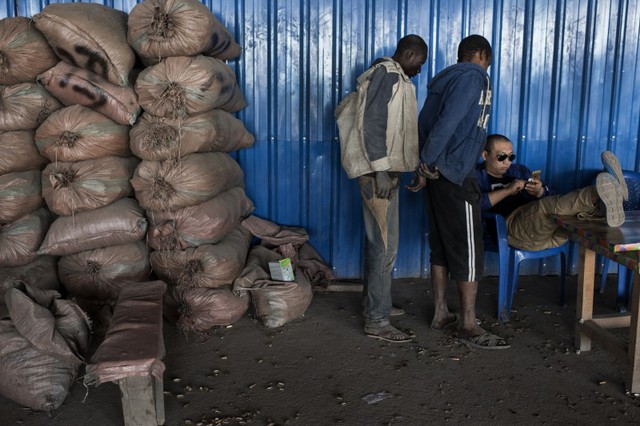 Một người đàn ông Châu Á đang ngồi tính tiền để trả cho các thợ đào ở chợ Musomp.