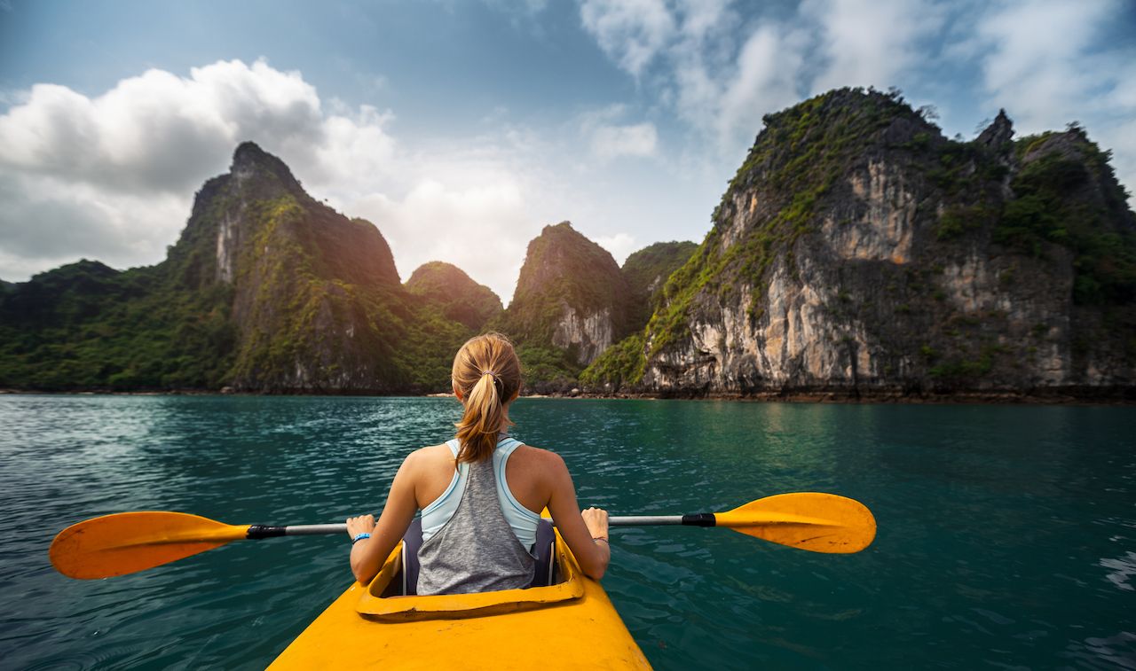 Woman-exploring-calm-tropical-bay-with-limestone-mountains-by-kayak.jpg