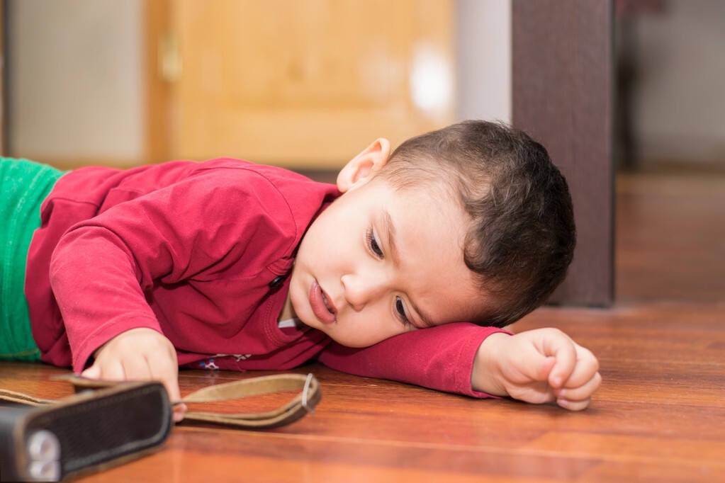 Лежа играть в телефон. Мальчик лежит на полу. Мальчик валяется на полу. Дошкольник лежит на полу. Ребенок лежит на полу.