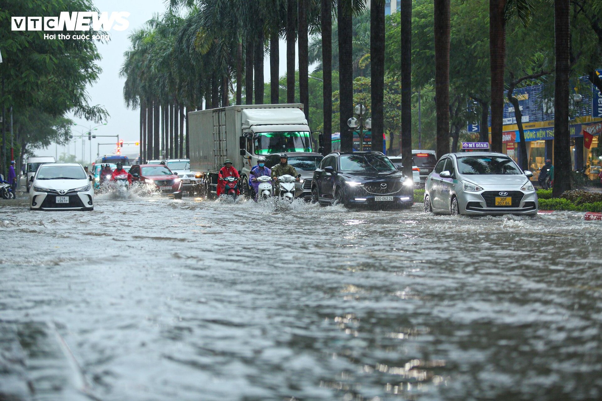 Người Hà Nội 'bơi' trên phố, hì hục tát nước khỏi nhà sau trận mưa như trút - Ảnh 1.