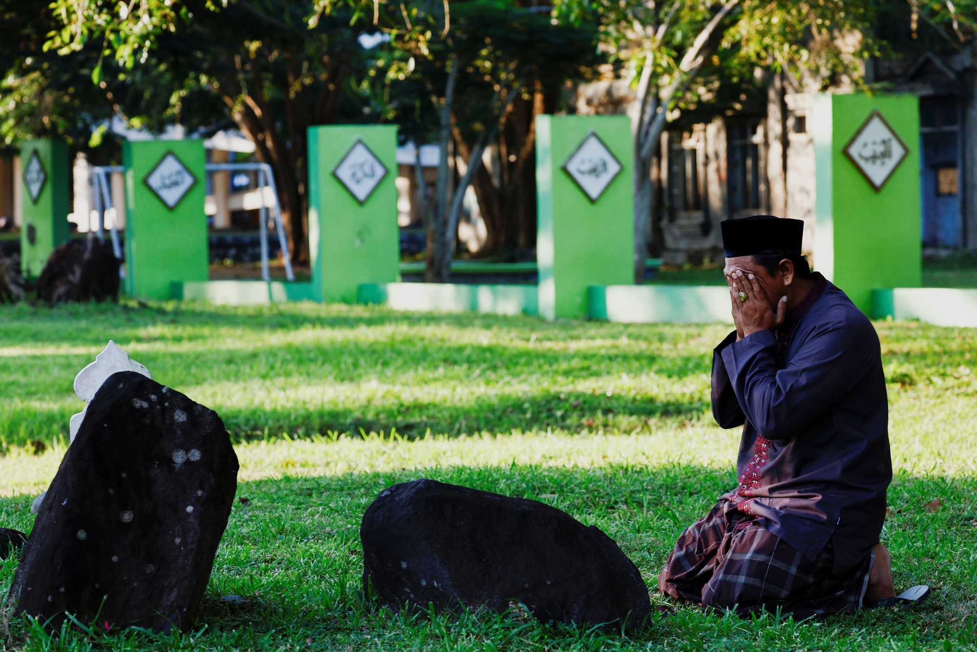 Một người đàn ông cầu nguyện tại ngôi mộ tập thể ở làng Ulee Lheue, TP BandaAceh - Indonesia  ngày 26-12. Ông đã mất nhiều người thân trong thảm họa sóng thần năm 2004Ảnh: Reuters