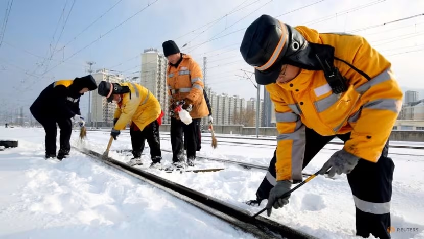 Nhân viên dọn băng tuyết trên đường ray dọc theo ga đường sắt phía Đông Liên Vân Cảng, ở tỉnh Giang Tô. Ảnh: Reuters