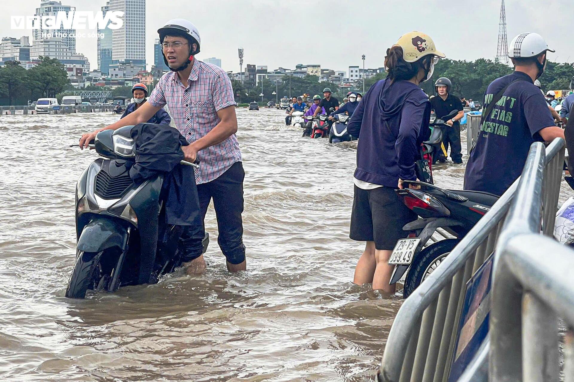 Đường vẫn ngập ngang gối, dân Hà Nội chen chúc dắt xe lội nước đi làm từ sớm Đường vẫn ngập ngang gối, dân Hà Nội chen chúc dắt xe lội nước đi làm từ sớm