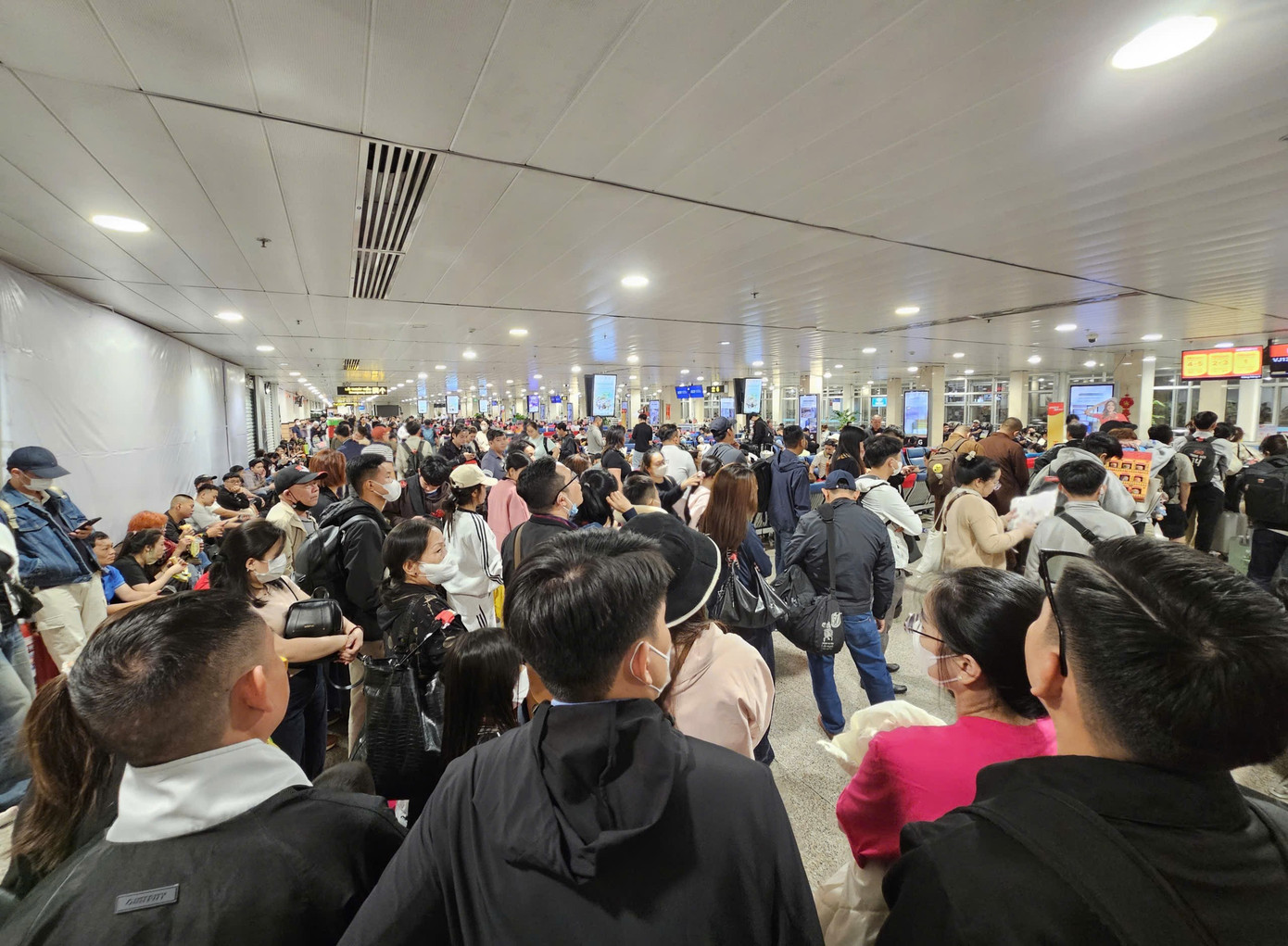 Hành khách chờ đêm tại sân bay Tân Sơn Nhất trong ngày cao điểm Tết 2026 - Ảnh 1.