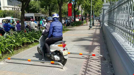 Một trường hợp lách vào khoảng hở giữa hai thanh barie để đi trên vỉa hè tại đoạn trước Bảo tàng TP.HCM. Ảnh: NHĐ