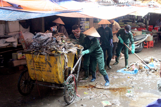 Lực lượng dọn vệ sinh gồng mình dọn rác sau mưa lớn tại chợ Vinh. Ảnh: Quang An