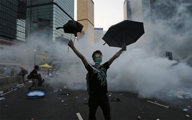 Một người biểu tình đòi dân chủ ở Hồng Kông giương ô trong làn khói hơi cay của cảnh sát chống bạo động ở quận trung tâm thành phố hôm 28/9. Cuộc biểu tình đòi bầu cử dân chủ do sinh viên dẫn đầu ở Hồng Kông đã kết thúc sau gần 3 tháng mà không đạt được sự nhượng bộ nào từ phía chính quyền - Ảnh: Reuters.