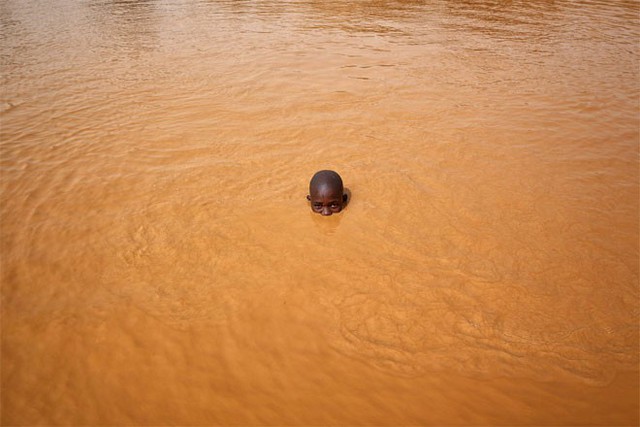 Abdul Haruna, 14 tuổi, là một trong số hàng trăm đứa trẻ làm việc ở mỏ vàng Djuga. Cậu bé đang tắm sau một ngày làm việc dài.