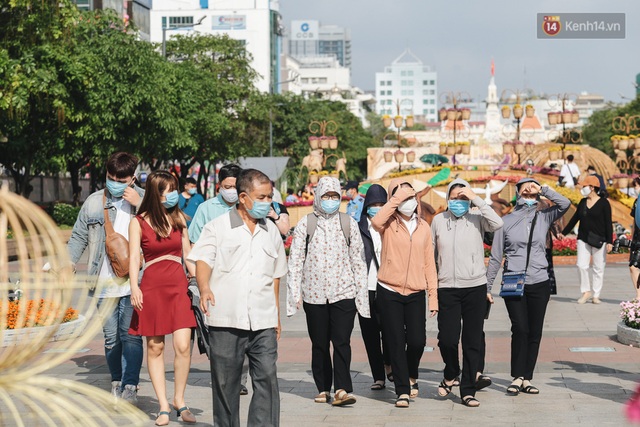 Ảnh: Người Sài Gòn xếp hàng đo thân nhiệt, đeo khẩu trang vào check in đường hoa Nguyễn Huệ - Ảnh 5.