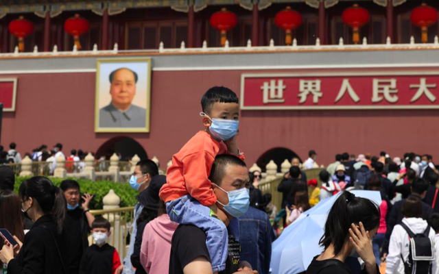 Một bé trai ngồi trên cổ bố khi đi chơi ở quảng trường Thiên An Môn ngày 3/5. Ảnh: AP