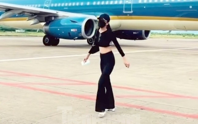 Nữ khách hồn nhiên tiến tới chiếc máy bay đang lăn vào vị trí đỗ bên cạnh để quay video đưa lên mạng xã hội, nữ khách chỉ quay lại khi sắp chạm vạch đỏ giới hạn an toàn giữa 2 vị trí đỗ máy bay. (Ảnh: Tiền phong)