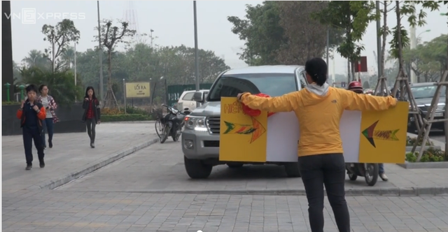 Bà mẹ người Hàn Quốc cầm biển báo ngăn dòng xe máy chạy lên vỉa hè tại Mễ Trì.