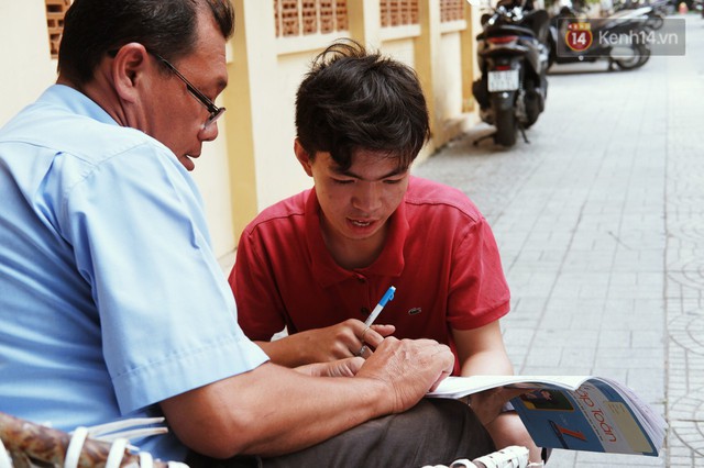 Lớp học đáng yêu trên vỉa hè: Một bác bảo vệ vừa giữ xe vừa dạy chữ cho cậu nhóc bán hàng rong ở Sài Gòn - Ảnh 1.