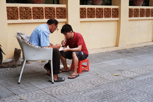 Lớp học đáng yêu trên vỉa hè: Một bác bảo vệ vừa giữ xe vừa dạy chữ cho cậu nhóc bán hàng rong ở Sài Gòn - Ảnh 4.
