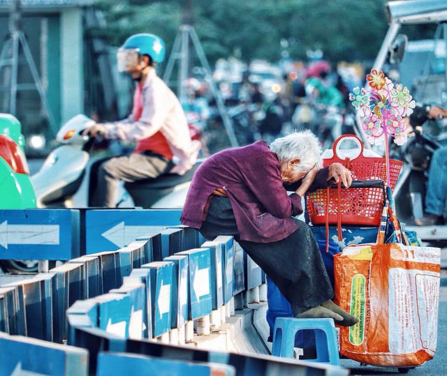 Hình ảnh cụ bà lưng còng gục đầu bên gánh hàng rong giữa ngã tư Hà Nội khiến nhiều người xót xa - Ảnh 1.